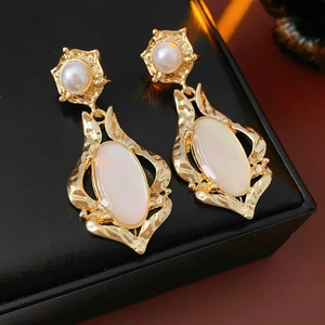 Gros plan de boucles d'oreilles vintage en nacre dorée et perle sur cuir noir