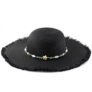 Detail of black straw sun hat with starfish bead trim and frayed tassel brim edge