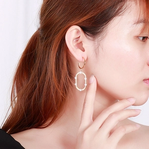 Gros plan d'une boucle d'oreille ovale en or avec zircons blancs sur un mannequin
