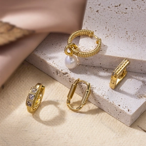 Selection of geometric gold hoop earrings with pearls and zircons on beige stones