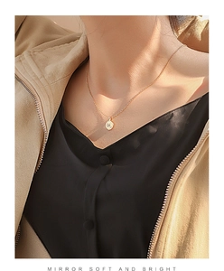 Close-up of a minimalist gold coin necklace with a star detail worn by a model