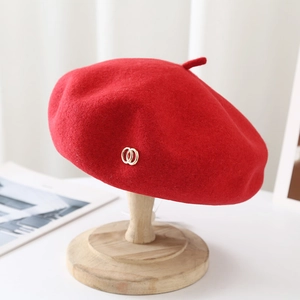 Detailed texture of red wool tweed beret with elegant double interlocking gold metal rings