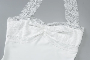 Dettaglio delle spalline in pizzo bianco e della trama del tessuto sul vestito attillato