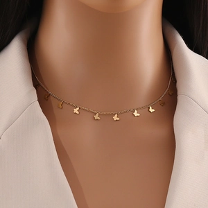 Close-up of a minimalist gold butterfly necklace worn with a professional white blazer