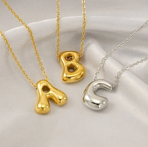Close-up of balloon-style A, B, and C letter pendants in gold and silver steel
