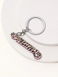 Dettaglio del portachiavi MAMA con stampa leopardata e accenti rosa su vassoio bianco pulito