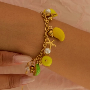 Close-up of a summer charm bracelet with fruit pendants and starfish on a wrist