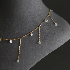 Macro view of gold plated tassel necklace with sparkling round zircon crystals on a model