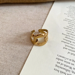 Detailed view of a gold chain style open ring on vintage book pages and linen cloth