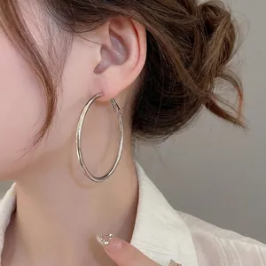 Minimalist large silver hoop earrings with polished metal finish on a female model