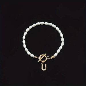 Elegant white oval pearl bracelet featuring a gold OT toggle clasp and rhinestone letter U charm