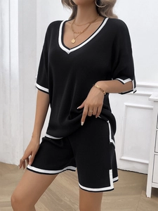 Detailed view of women's black V-neck knit top and shorts with white contrast stripes