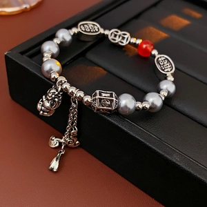 Detailed shot of beaded bracelet with dragon charm, red agate, and pearl accents