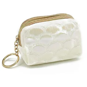 Macro detail of pearlescent white mini coin purse with fish scale embroidery and gold ring