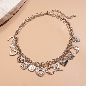 Silver geometric necklace with moon, heart, and boot charms on textured stone background