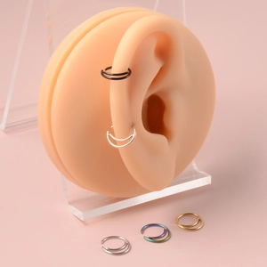 Set of surgical steel septum rings and ear hoops shown on a silicone ear model display