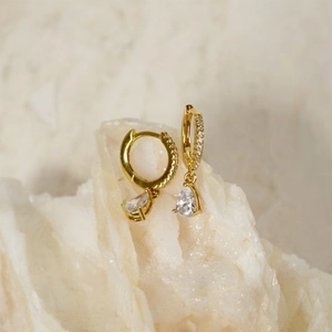Detail of gold teardrop earrings featuring a pavé huggie hoop and pear-cut zircon stone