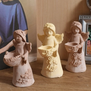 Three angel resin sculptures holding flower baskets displayed on a wooden shelf