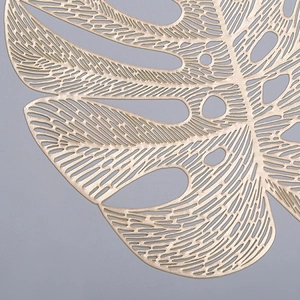 Detailed close-up of hollowed-out golden monstera leaf placemat with metallic finish