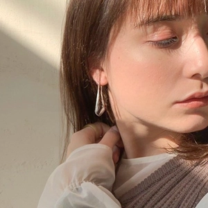 Elegant silver-tone elongated U-shaped teardrop earring worn by a model in natural sunlight