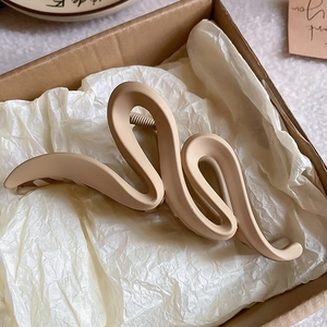 Macro detail of a large wavy acrylic hair claw clip with matte finish in light brown color