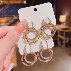 Detailed view of intertwined golden ring earrings featuring cat eye stone and cubic zirconia