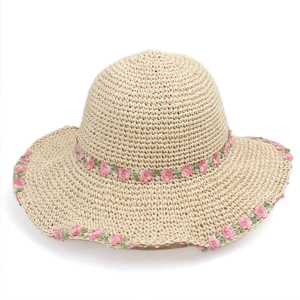 Close-up of woven straw texture and delicate pink flower embroidery on a sun hat