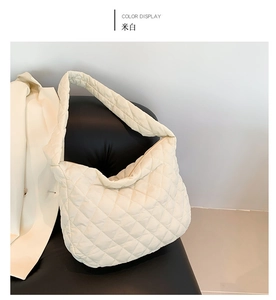 Detailed view of the off-white quilted puffer tote bag on a black leather seat