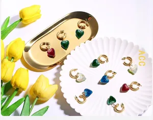 Detail of heart-shaped charms on gold metal hoops in deep green, burgundy and blue