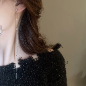 Detailed view of silver tassel earrings with zircon stones worn by a fashion model
