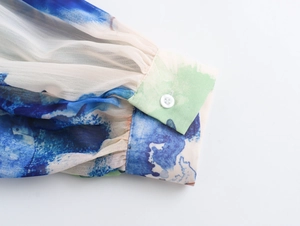 Λεπτομέρεια από σιφόν μανίκι με tie-dye τύπωμα και λευκό κουμπί στη μανσέτα