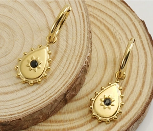 Detail of 18K gold teardrop earrings featuring a black gemstone with sunburst patterns