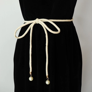 Elegant cream woven knot belt with pearl tassels styled on a black velvet dress