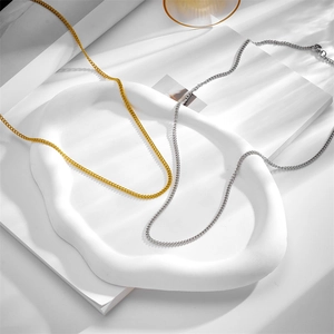 Detail view of gold and silver stainless steel chain necklaces on a white textured display tray