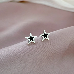 Close-up of star-shaped titanium steel studs on pink satin showing black enamel inlay