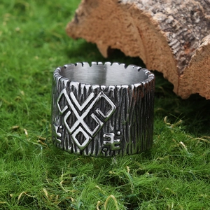 Macro shot of silver vintage Viking ring with wood grain texture on green moss background