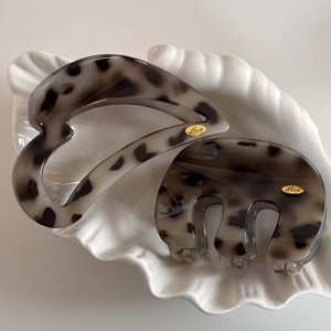 Detail of two tortoise shell hair claws with gold Love labels on white ceramic plate