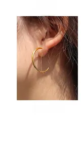 Dettaglio di grandi orecchini a cerchio in oro 18K lucido su modella con stile minimal