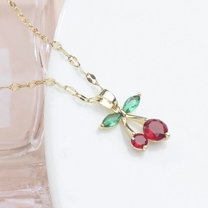 Sparkling red cherry pendant necklace with gold chain and green marquise gems