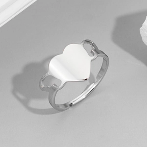 Silver vintage open heart ring with hollow wing detail on minimalist stone display