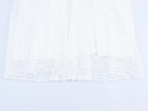 Close-up of white lace fabric detail with hollow embroidery and scalloped wave patterns