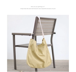 Detail of mustard yellow canvas bag showing durable material and secure metal snap closure