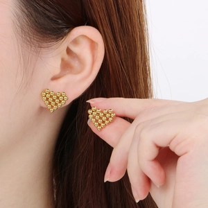 Golden heart-shaped beaded stud earrings in stainless steel on model with size comparison