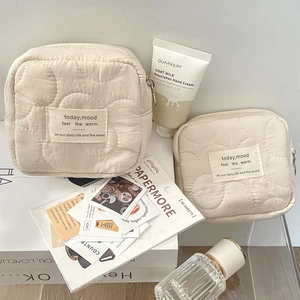 Quilted beige cosmetic pouches with mood quotes and soft fabric texture in lifestyle setting