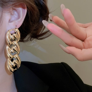 Close-up of elegant gold thick chain-link earrings on model with a high-fashion aesthetic
