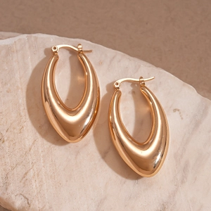 Glossy gold hollow teardrop earrings on textured stone with elegant metallic shine
