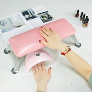Detail of pink PU leather manicure footrest with silver metal legs and LED nail lamp below