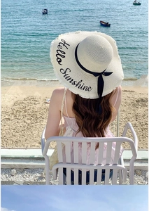 Close-up of beach straw hat with Hello Sunshine embroidery and black bow ribbon detail