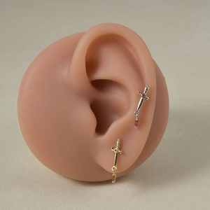 Detail of sword-shaped ear studs with orange teardrop gemstone on silicone model