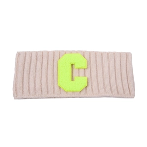 Détail macro du bandeau en maille côtelée beige avec un patch lettre C vert néon